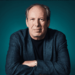 Hans Zimmer sitting and smiling with his arms crossed